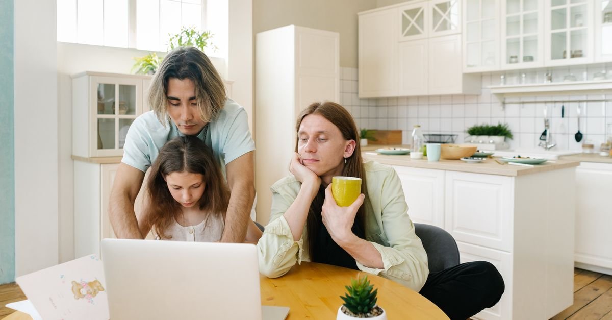 A family spends quality time together in a modern kitchen, focused on a laptop.